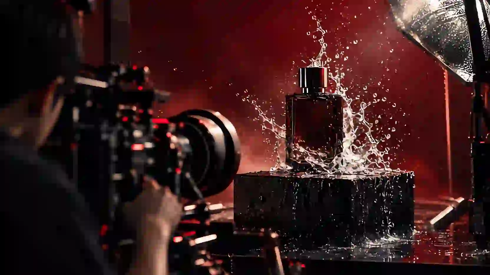 Commercial shoot: water splashes around an unlabelled glass bottle under a hard silver light.